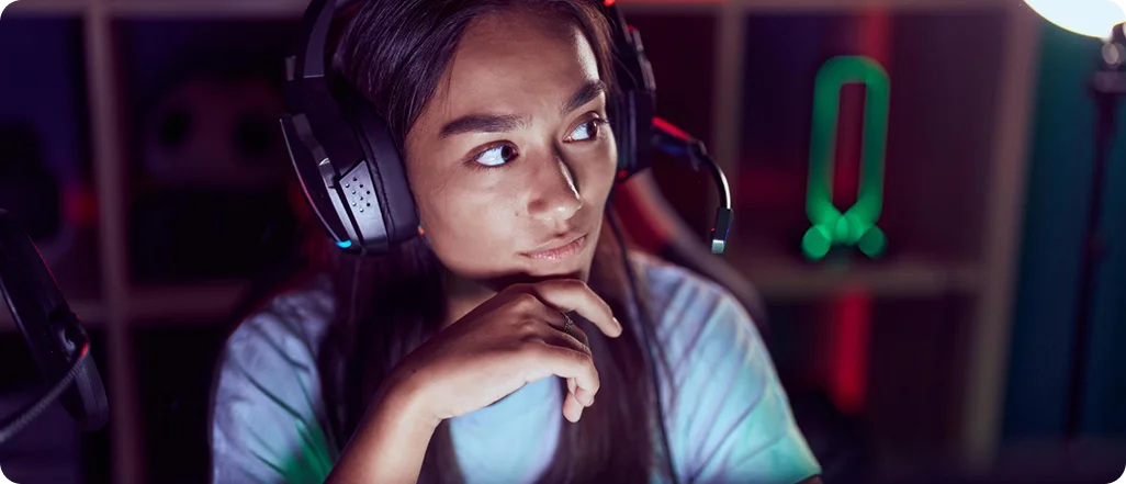 Geconcentreerde vrouwelijke gamer met koptelefoon, aandachtig kijkend naar het scherm in een moderne gamingomgeving met RGB-verlichting.